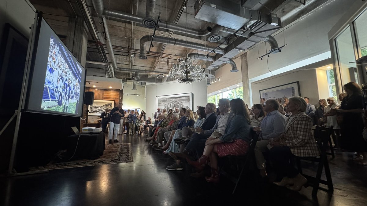 An audience seated in rows facing a projection screen at an indoor event