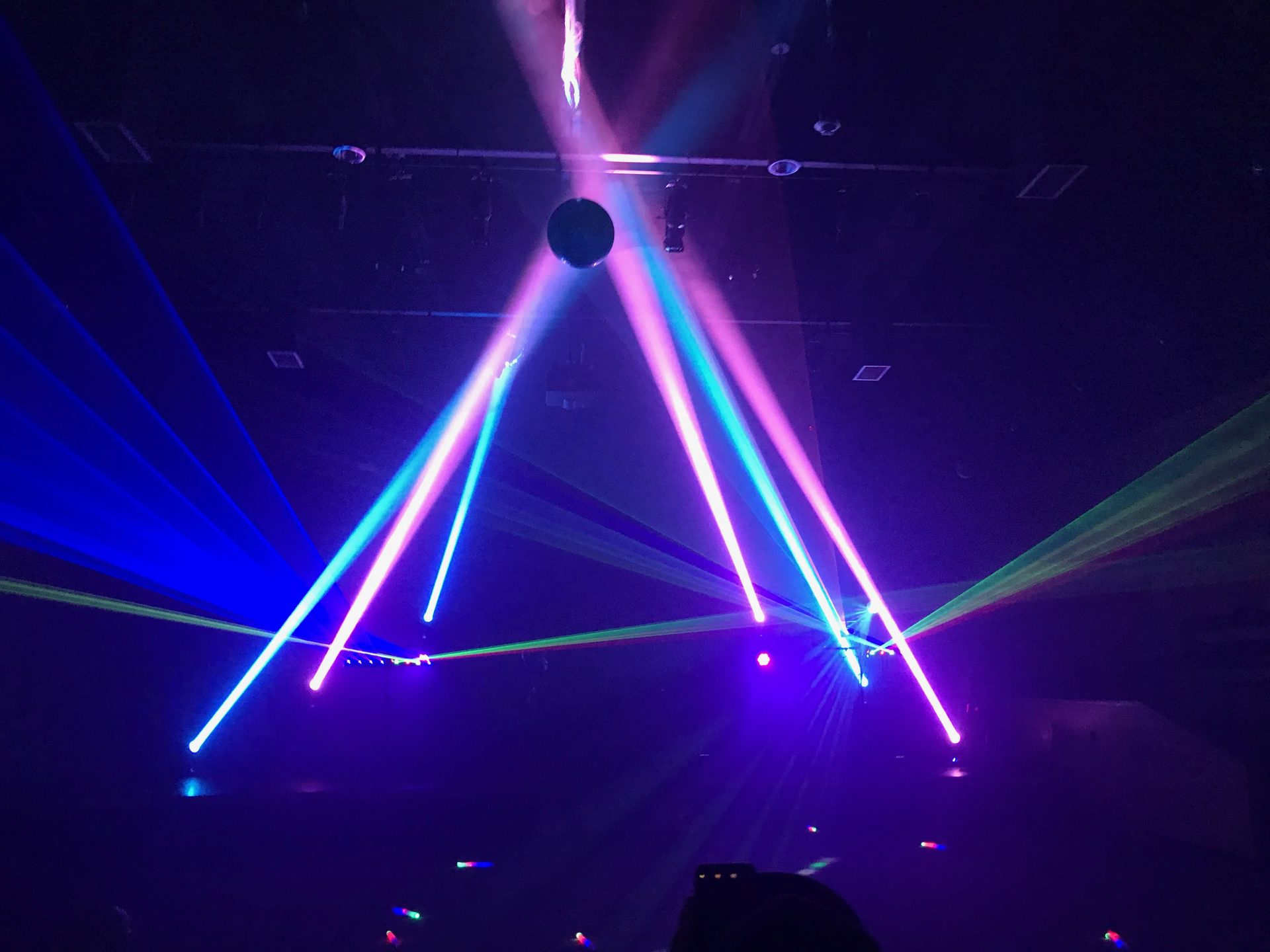 Laser beams crossing beneath a mirror ball at a Dallas event